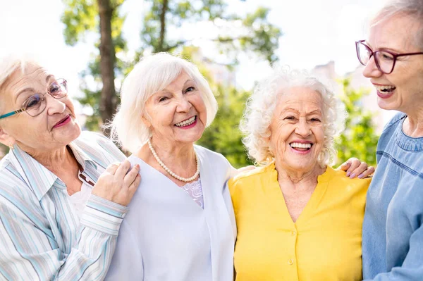 Group of happy elderly people bonding outdoors at the park - Old people in the age of 60, 70, 80 having fun and spending time together, concepts about elderly, seniority and wellness aging