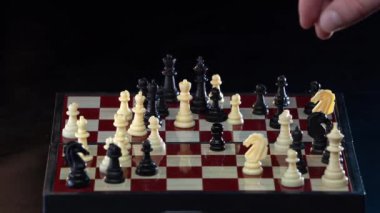 Erkek el, siyah arka planda izole edilmiş beyaz atlı şövalyeyle hamle yapıyor. Satranç oynayan bir iş adamı. Rekabet, spor ve strateji konsepti. 4k