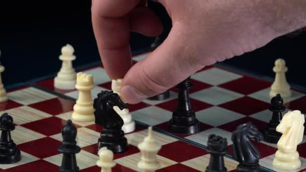 Sakk játék. Ember teszi lépés fehér püspök a sakktáblán alatt sakk játék elszigetelt fekete alapon. Chessman fadarabokkal játszik. Intelligencia és stratégia koncepció. 4k felvétel — Stock videók
