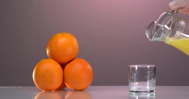 A nő friss narancslevet tölt az elektromos facsaróból három pohárba, közelről. Egészséges vegán érett gyümölcslé, természetes vitaminok az ételből. Vegán egészséges organikus táplálkozás. — Stock videók