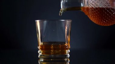 Barmen konyakla bardağı karıştırır. Viski ve buzla bardağı karıştırır. Barmen viski ve kolayla kokteyl yapar..