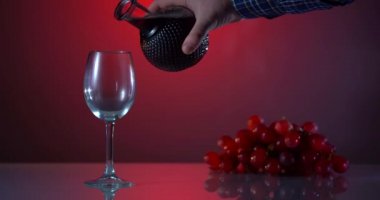 Masada kırmızı şarap ve taze üzüm tadı. Tatil çekimi. Reklamcılık kırmızı arkaplanda bir kadeh kırmızı şarap. Reklam çekimi. Sarmaşığın ilerlemesi.