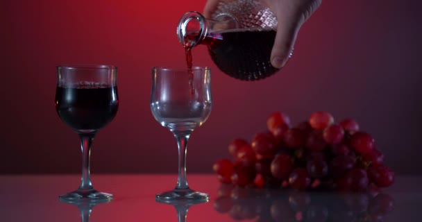 Wijn. Rode wijn giet uit de hals van de fles in wijnglas over donkere achtergrond. Rozenwijn die uit de fles komt. Reclamemateriaal — Stockvideo