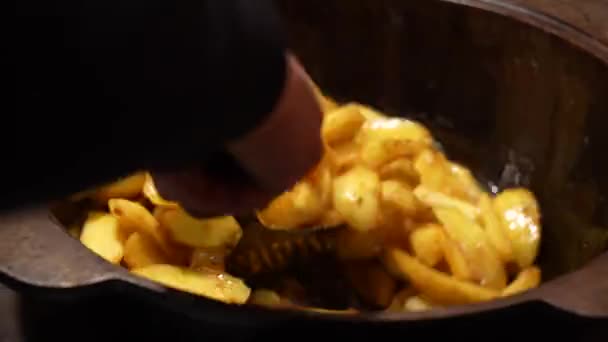 Gătesc cartofi. Omul amestecând mâncarea într-o tigaie cartofii prăjiți de aur condimentați cu ulei, sare și piper negru pe o tigaie de copt. Procesul de gătire a alimentelor gustoase. — Videoclip de stoc