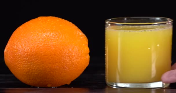 Ahşap arka planda bir bardakta taze portakal suyu. Taze portakal meyveleri. Sağlıklı vejetaryen yemeği. Vitamin yiyeceği. Olgun portakallar. Adam çerçeveye cam koymuş. — Stok video