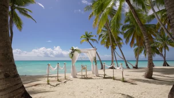 Όμορφη γαμήλια παραλία που έχει συσταθεί διακοσμημένα με ύφασμα και λουλούδια σε εξωτερικούς χώρους.Γάμος αψίδα έννοια. γάμος στο νησί παραλία καλοκαιρινές διακοπές. Παλάμες και μπλε ωκεανός. Ρομαντικός τροπικός γάμος — Αρχείο Βίντεο