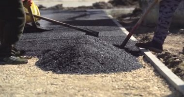 Yol yapımında çalışan inşaat işçileri Sıcak Asfalt yüzeyinden buhar yükseliyor. Yol inşaatında asfalt döşeyen işçiler. Kaldırımı hazırlayın.