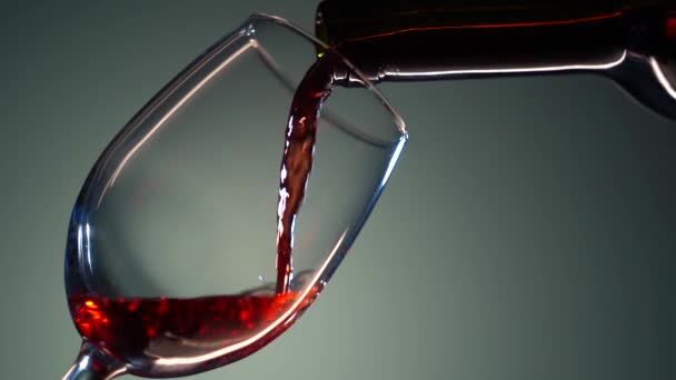 Медленное движение наливания красного вина из бутылки в бокал. Крупный план красного вина образует красивую волну в стакане. Вино наливается в стекло на белом фоне. — стоковое видео
