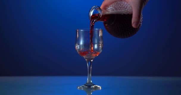 青い背景のガラスに赤ワインを振るワインのコマーシャルのための美しいストック映像。広告撮影。広告 — ストック動画