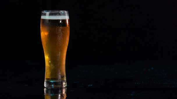 Een biertje. Cold Craft light Bier in een glas met waterdruppels. Advertentiefoto. Advertentie concept. Man hand neemt lekker koud bier. Zwarte geïsoleerde achtergrond. — Stockvideo