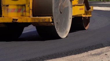 Yol yapımında yeni asfalt yapıyorum. Yol inşaatında çakıl döşeyen bir yol silindiri. Kaldırım ya da asfalt makinesi ziftlenmiş. Patenler levele ve yeni asfalt sıkıştırıyor. Yol yüzeyi onarımı