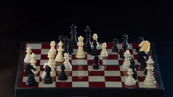 Шахматный мат на деревянной шахматной доске. Мужская рука, двигающая белую королеву, побеждает черного короля. Шах и мат. Грандмастер делает стратегический ход и побеждает противника делая шах и мат изолирован на черном — стоковое видео
