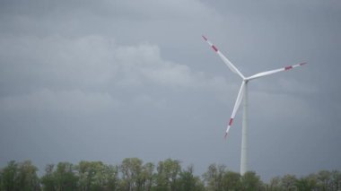 Parlak turuncu günbatımında bıçakları olan büyük rüzgar türbinleri. Mavi gökyüzü parkı yavaş çekim drone dönüşü. Siluetler yel değirmenleri, büyük turuncu güneş diski yaz merceği parlamaları. Alternatif enerji. 4k