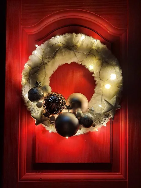 Kırmızı arka planda küçük lambalar olan Noel çelengi.