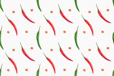 Kırmızı ve yeşil biberli kusursuz baharat deseni çapraz, beyaz arka planda kesilmiş kırmızı biber dilimleri. Sağlıklı yeme kavramı