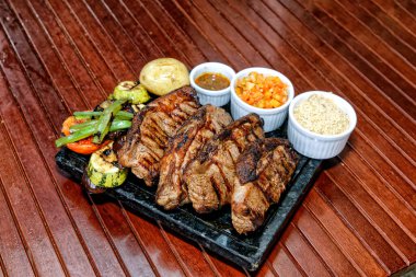 Ahşap bir tahtada ızgara domuz pirzolası ve sos.