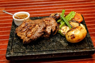 Ahşap bir tahtada ızgara domuz pirzolası ve sos.