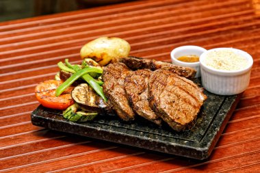 Ahşap bir tahtada ızgara domuz pirzolası ve sos.