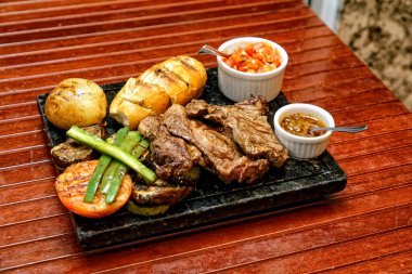 Ahşap bir tahtada ızgara domuz pirzolası ve sos.