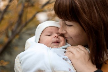 annenin doğum yenidoğan parkta sonbaharda eller.
