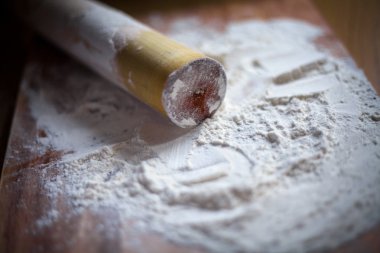 bir kesme tahtası üzerinde bir oklava ile un