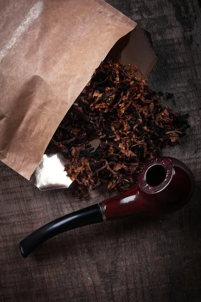 Табак и труба на деревянной поверхности — стоковое фото