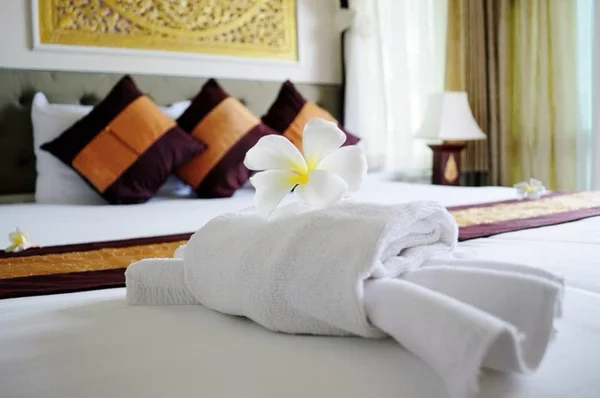 Белая игрушка в форме краба и цветок франжипани на белой кровати в комнате отдыха роскошного бутик-отеля Стоковое Изображение
