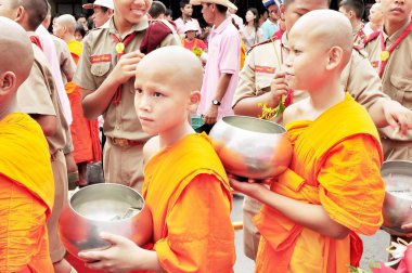 Taylandlı genç Budist keşişler yemek ve erdem isteyen insanlardan yiyecek almak için sıraya giriyorlar - Tayland