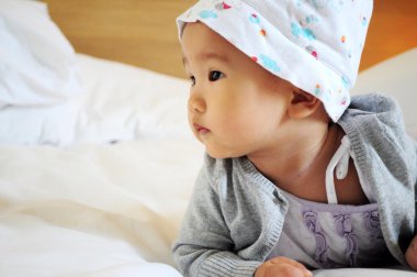 Beyaz yatakta şapkalı çocuk