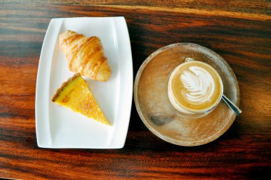 ahşap üzerine bir fincan sıcak kahve, kruvasan ve tutku meyve tart ta