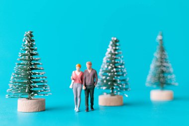 Minyatür insanlar, birbirine aşık bir çift Noel ağacının yanında duruyor, Noel ve mutlu yıllar konsepti.
