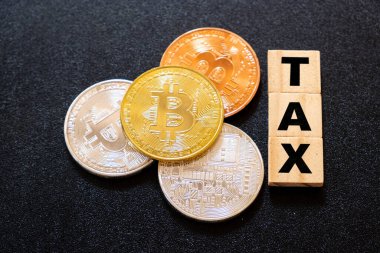 Koyu ahşap arka planda vergi sözcüğüne sahip kripto para birimleri