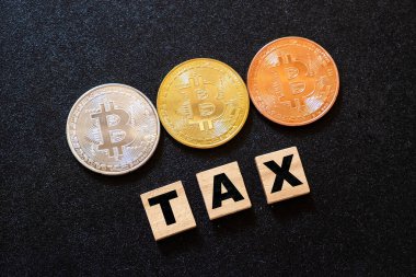 Koyu ahşap arka planda vergi sözcüğüne sahip kripto para birimleri