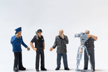 Minyatür insanlar, mikrofonlu haber muhabiri ve kameraman polislerle röportaj yapıyor.