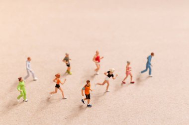 Miniature People exercising while running in a group on the beach. Living an active lifestyle concept
