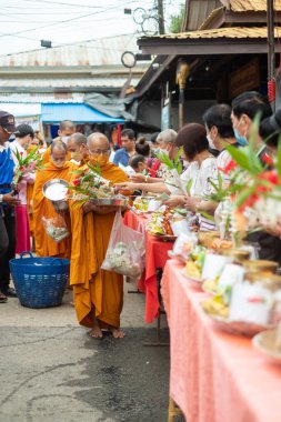 Songkhla Buri, Kanchanaburi, Tayland - 26 Haziran 2022: Budist rahipler sabah erken saatlerde yerel halktan sadaka ve yiyecek alıyorlar.