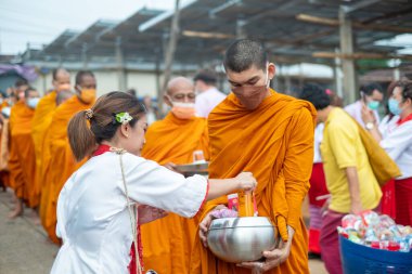 Songkhla Buri, Kanchanaburi, Tayland - 26 Haziran 2022: Budist rahipler sabah erken saatlerde yerel halktan sadaka ve yiyecek alıyorlar.