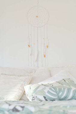 Duvarda asılı bir yatak odasında düş kapanı ya da makrome. Bohem, uyumlu bir hayat ve iyi ruhlarla tatlı rüyalar. Boho şıklığı, etnik tılsım ve sembol, rahat beyaz iç tasarım.