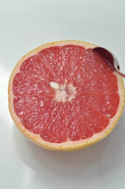 Pembe greyfurt ikiye bölünmüş. Kaşıkla greyfurt yemek. Sulu narenciye. Kilo vermek için lezzetli, lezzetli ve sağlıklı bir diyet. Kahvaltıyı tazeliyorum..