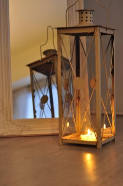 Romantik fener yansıması. Dekoratif ayna çerçevesi. Mum ışığı alevini rahatlatıyor. Huzurlu bir ev..