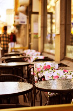 Mağaza vitrinlerinde reklam tabelaları. Yemek turistleri için romantik bir açık hava restoranı. Arka planda tatil turistlerini görmek.