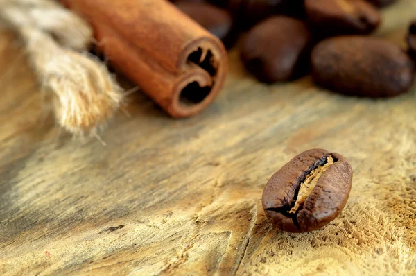 Chicchi di caffè e cannella bastoncini su sfondo di legno — Foto Stock