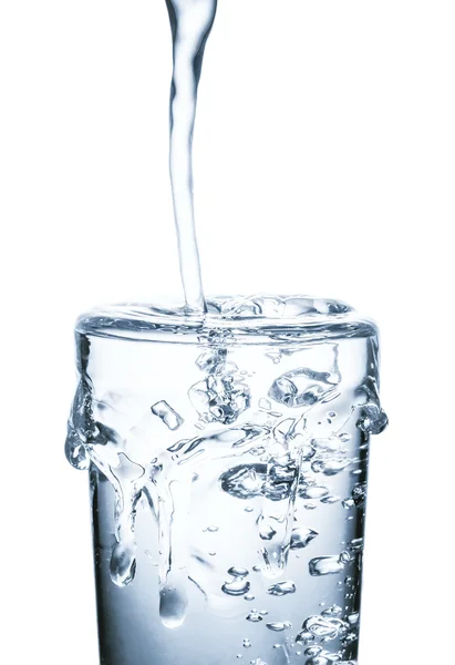 Agua vertiendo en vidrio aislado sobre fondo blanco — Foto de Stock