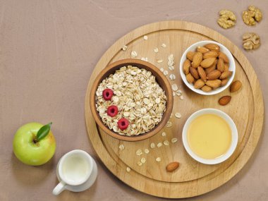 Yulaf gevreği, ahududu, badem, ahşap zemin üzerinde bal. Sütçü, ceviz, yeşil elma. Doğru kahvaltı ya da akşam yemeği. Ürünlerin sinerjisi. Üst Manzara. Mesaj için yer var. Yüksek çözünürlüklü mikrografi.