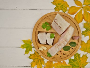 Pastırma, sarımsak, kişniş, defne yaprağı, ahşap arka planda biber. Sonbahar yaprakları beyaz ahşap bir masada. Lezzetli ve sağlıklı yiyecekler. Mesaj için yer var. Üst görünüm