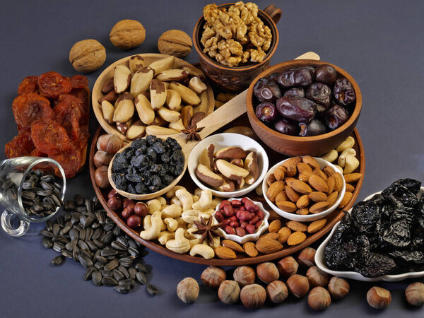 Assorted nuts. Walnuts, cashews, brazil nuts, almonds, peanuts, hazelnuts. Dried fruits. Dried apricots, prunes, raisins, dates. Close-up. Macrophotography. Proper nutrition. Side view. Space for text.