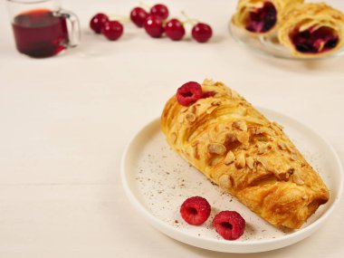 Cookies, raspberry jam cake, fresh raspberries. On a white background. In the background there is a cherry, a glass of juice, a bun. Selective focus. copy space