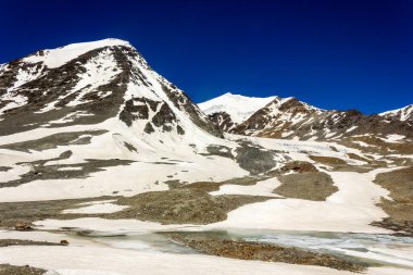 Karlı dağ zirvelerinin güzel manzarası uzak yabanda bir buzulun kenarında Zanskar 'daki Shingo La' nın yüksek rakımlı geçidine doğru yol alıyor..