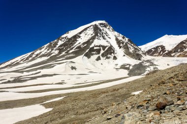 Karlı dağ zirvelerinin güzel manzarası uzak yabanda bir buzulun kenarında Zanskar 'daki Shingo La' nın yüksek rakımlı geçidine doğru yol alıyor..