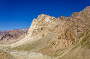 Kuzey Hindistan 'ın Ladakh bölgesinde güneşli bir günde mavi gökyüzünün altında, Zanskar vadisinin soğuk çöl çöllerinin çorak dağları..